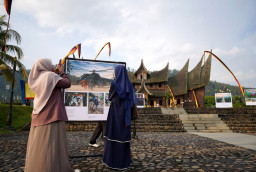 Pengunjung mengamati deretan karya foto bencana yang dipamerkan dalam pameran foto jurnalistik Prahara Pulau Emas di Istano Basa Pagaruyung, Senin (27/7/2026).