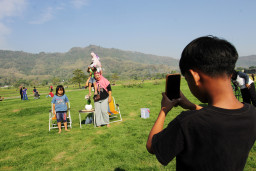 Sejumlah warga berfoto di sabana (padang rumput) di dasar Danau Gantiwarno yang mengering di Kabupaten Klaten, Jawa Tengah, Minggu, (26/7/2026). Berita Foto/Patrik Cahyo Lumintu
